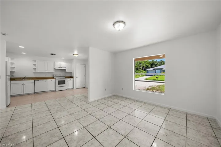 Unfurnished living room featuring light tile patterned flooring and baseboards