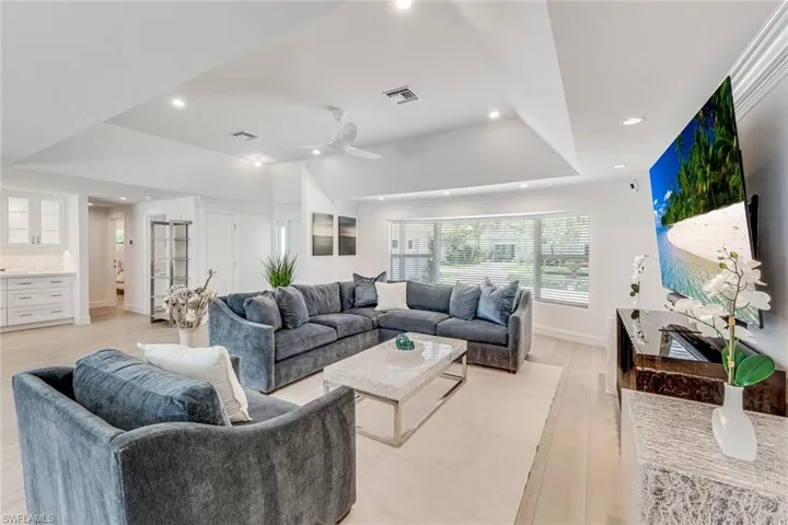 Spacious living area featuring light wood-finish flooring, recessed lighting, and a modern ceiling fan