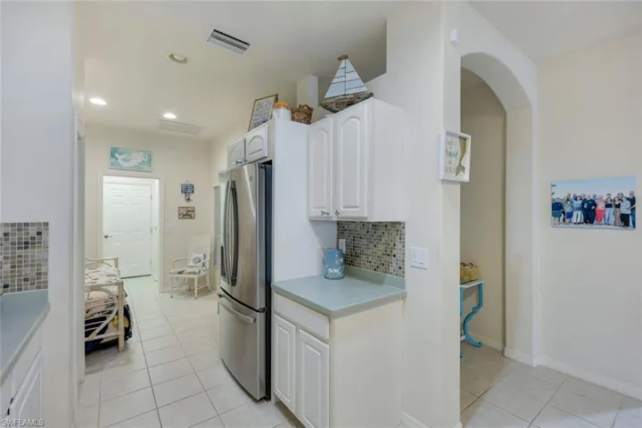 Kitchen with white cabinetry, stainless steel refrigerator, tasteful backsplash, and light tile patterned flooring
