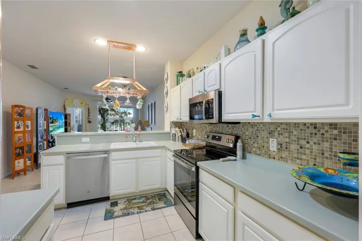 Kitchen with white cabinetry, backsplash, pendant lighting, and appliances with stainless steel finishes