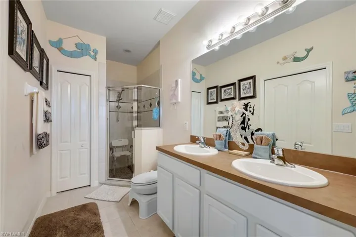 Bathroom featuring toilet, a shower with shower door, tile patterned floors, and vanity
