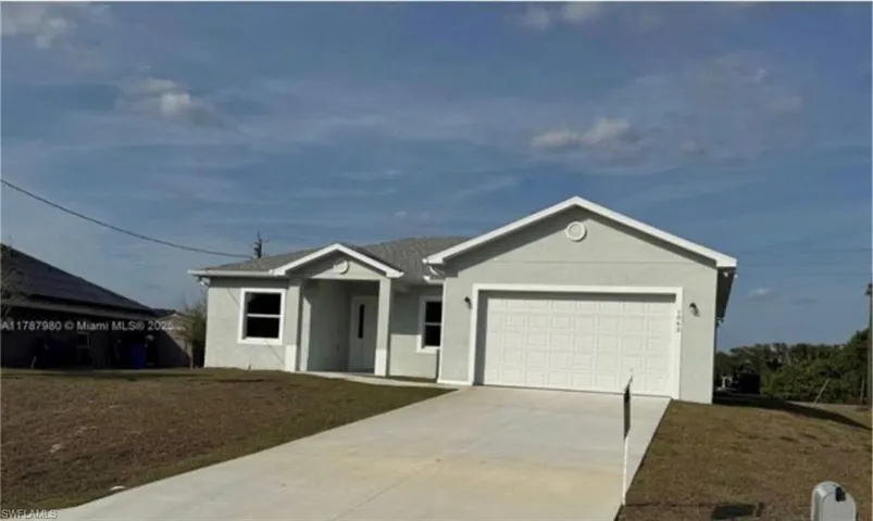 Ranch-style house with a garage, driveway, stucco siding, and a front yard