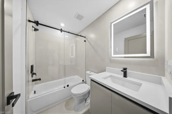 Unfurnished bedroom with a walk in closet, ceiling fan, a tray ceiling, and recessed lighting