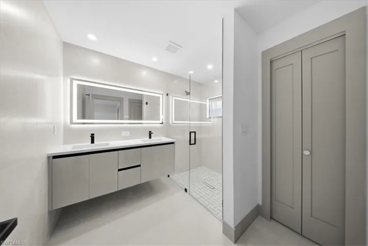Bathroom featuring double vanity, a stall shower, and recessed lighting