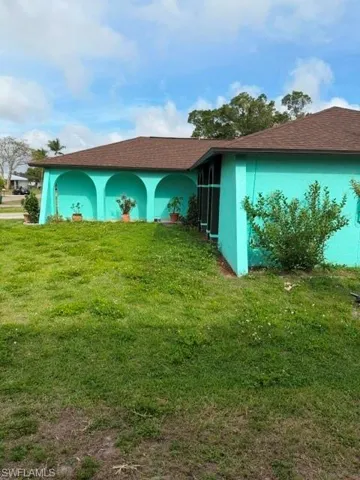 View of home's exterior with stucco siding, a lawn, and roof with shingles