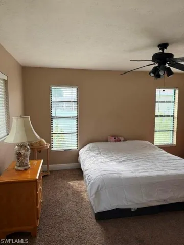 Bedroom featuring dark carpet, a textured ceiling, and ceiling fan
