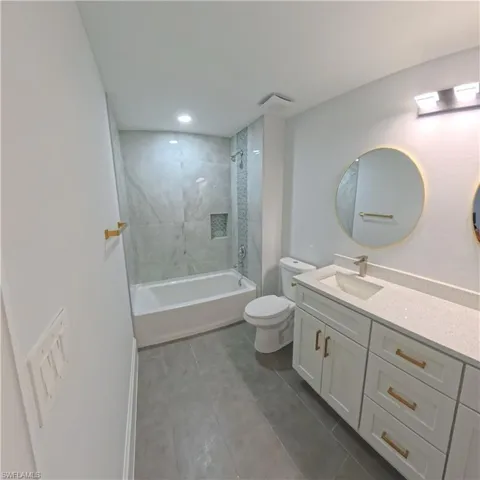 Bathroom featuring a combination bathtub and shower with a tiled surround, a built-in shower niche, and recessed lighting
