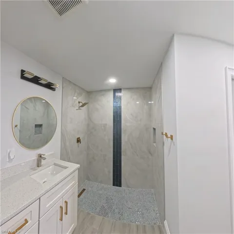 Modern bathroom featuring a walk-in shower with light gray tile and a dark blue accent stripe