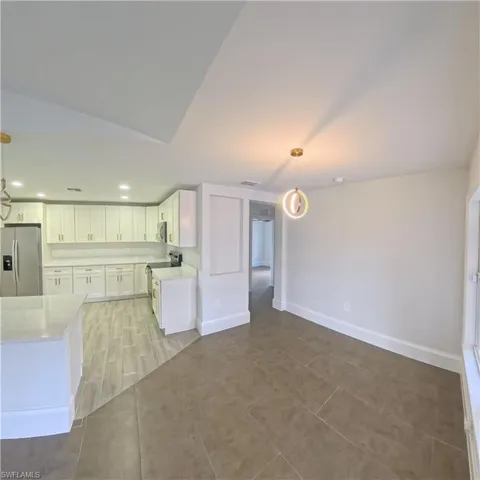 Open-concept living space with a contemporary kitchen, white shaker cabinetry, stainless steel appliances, and light-toned countertops