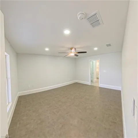 Spacious room featuring neutral paint, ceramic tile flooring, a ceiling fan with integrated lighting, recessed lighting, and white baseboards