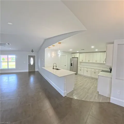 Open-concept living space with a kitchen island featuring a built-in sink and pendant lighting