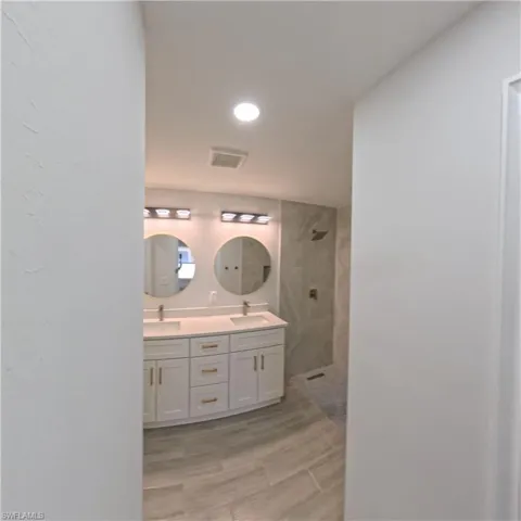 Dual vanity with white cabinetry, gold-toned hardware, and rectangular undermount sinks