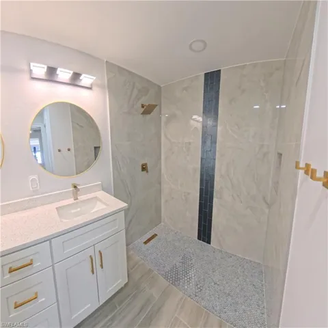 Contemporary bathroom featuring a walk-in shower with large format tile, a vertical accent tile strip, and a mosaic tile floor