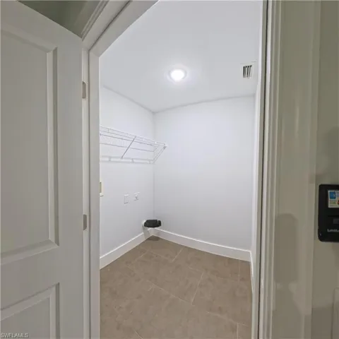 Utility room featuring tile flooring, white baseboards, and a wire shelving unit
