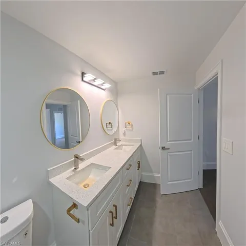 Dual vanity with white cabinetry and gold-tone hardware