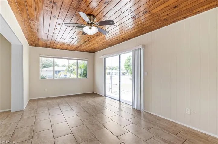 Unfurnished room featuring wooden ceiling, ceiling fan, light tile patterned floors, and wood walls