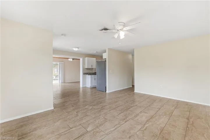 Unfurnished living room with ceiling fan and baseboards