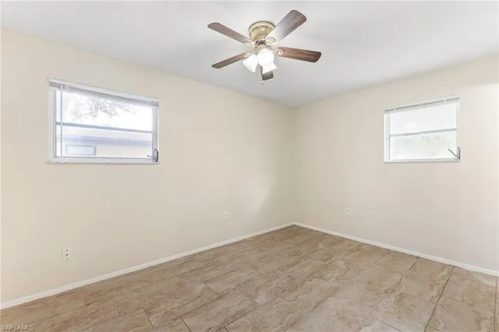 Empty room featuring ceiling fan and baseboards