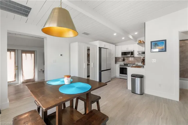 Dining room with lofted ceiling with beams, sink, light hardwood / wood-style flooring, and french doors