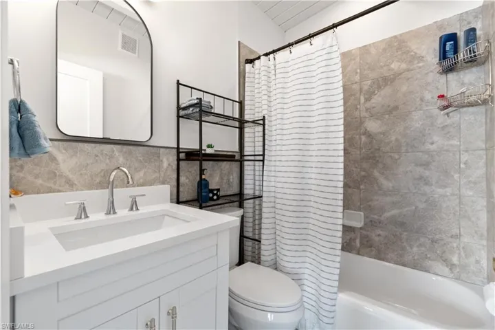 Full bathroom with vanity, tile walls, toilet, and shower / bath combo