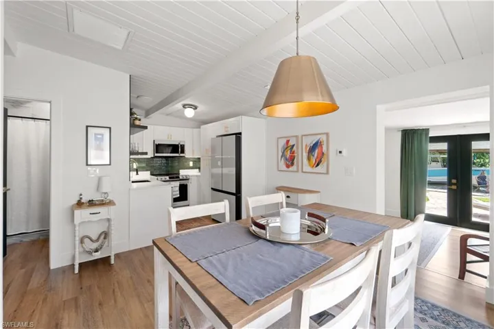 Dining area featuring french doors, sink, beam ceiling, and light hardwood / wood-style flooring