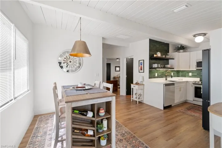 Kitchen featuring sink, white cabinetry, tasteful backsplash, hanging light fixtures, and stainless steel appliances