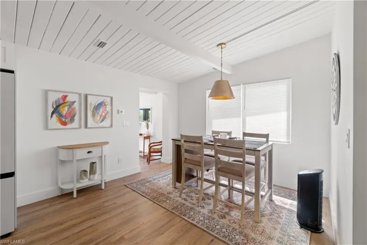 Dining area featuring beamed ceiling, a healthy amount of sunlight, wood ceiling, and hardwood / wood-style floors