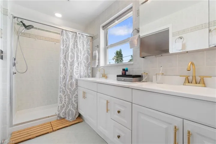 Bathroom featuring a shower with curtain, vanity, tile patterned floors, and decorative backsplash