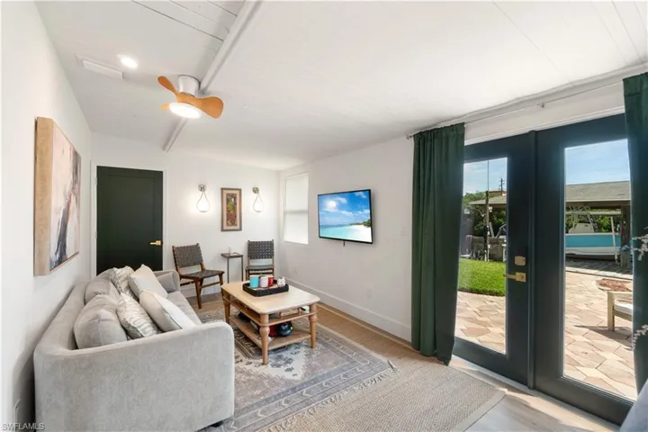 Living room with french doors, wood ceiling, beamed ceiling, ceiling fan, and hardwood / wood-style floors