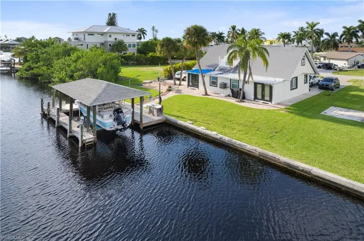 View of dock with a patio, a water view, and a lawn