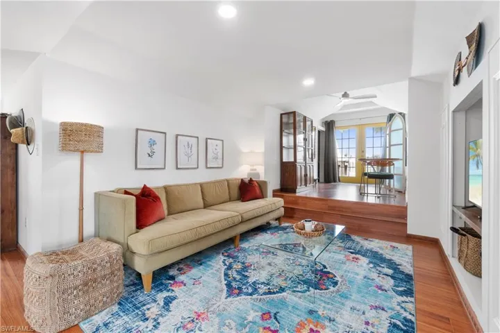 Living room featuring french doors, lofted ceiling, wood-type flooring, and ceiling fan