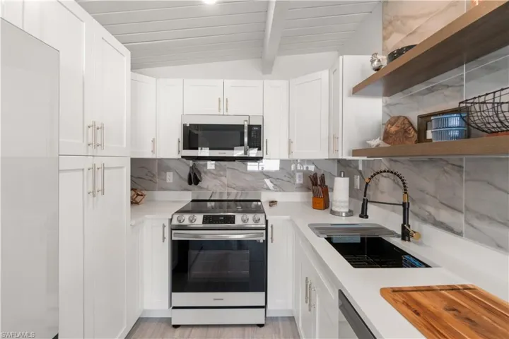 Kitchen with white cabinetry, stainless steel appliances, sink, and wooden ceiling