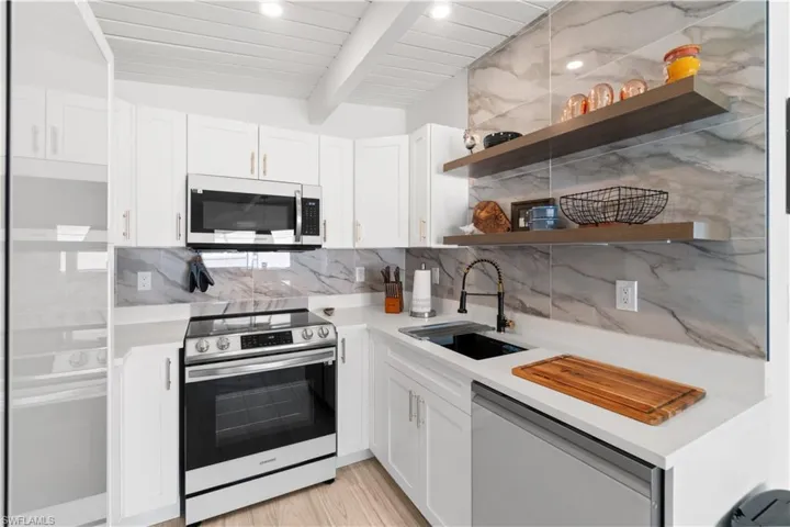 Kitchen featuring sink, light hardwood / wood-style flooring, wooden ceiling, appliances with stainless steel finishes, and white cabinets