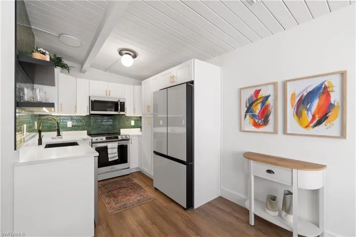 Kitchen featuring dark hardwood / wood-style floors, white cabinetry, sink, wood ceiling, and stainless steel appliances