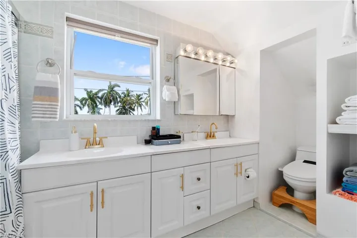 Bathroom featuring tile patterned floors, toilet, vaulted ceiling, vanity, and backsplash