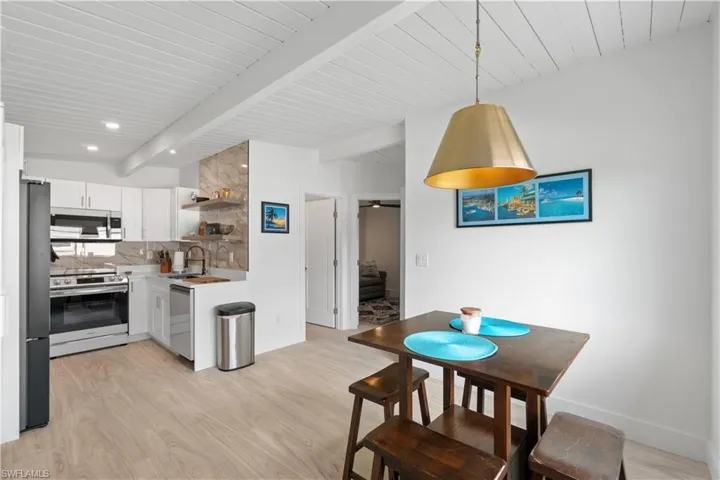 Kitchen featuring appliances with stainless steel finishes, decorative light fixtures, white cabinetry, sink, and decorative backsplash
