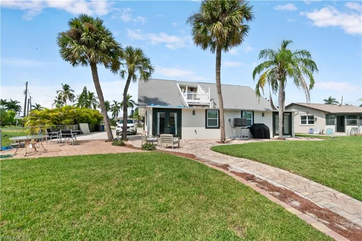 Rear view of property featuring a balcony, a yard, a patio area, and french doors