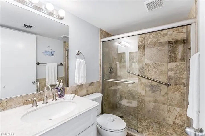 Full bath featuring vanity, a stall shower, and tile walls