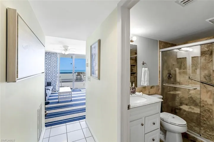 Full bathroom with a stall shower, vanity, light tile patterned floors, ensuite bath, and a ceiling fan