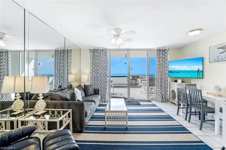 Living area featuring ceiling fan, expansive windows, and light tile patterned floors