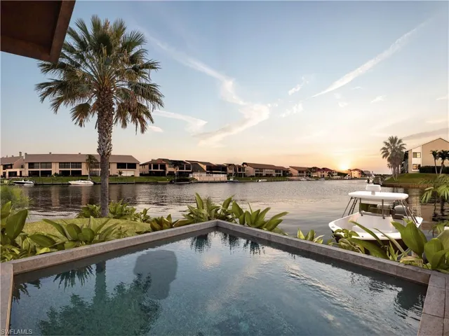 Pool at dusk with a water view, a residential view, and an outdoor pool