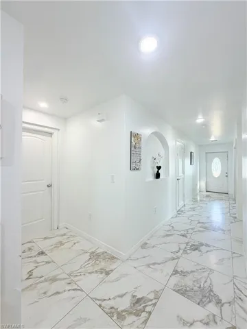 Hall with light marble finish floors and recessed lighting