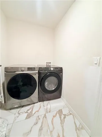 Laundry area with washing machine and clothes dryer and marble finish floors