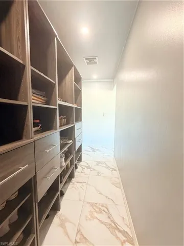 Spacious closet featuring light marble finish floors