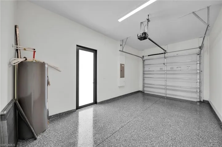 Garage featuring water heater, a garage door opener, and electric panel