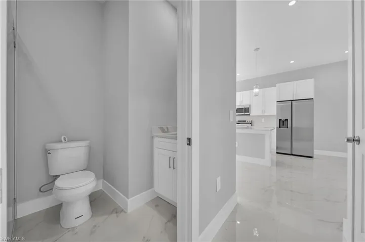 Half bath featuring light marble finish floors, vanity, and recessed lighting