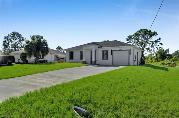 View of front of property featuring driveway, an attached garage, a front lawn, and stucco siding