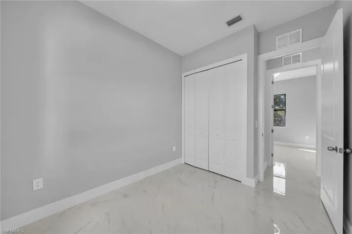 Unfurnished bedroom with light marble finish floors and a closet