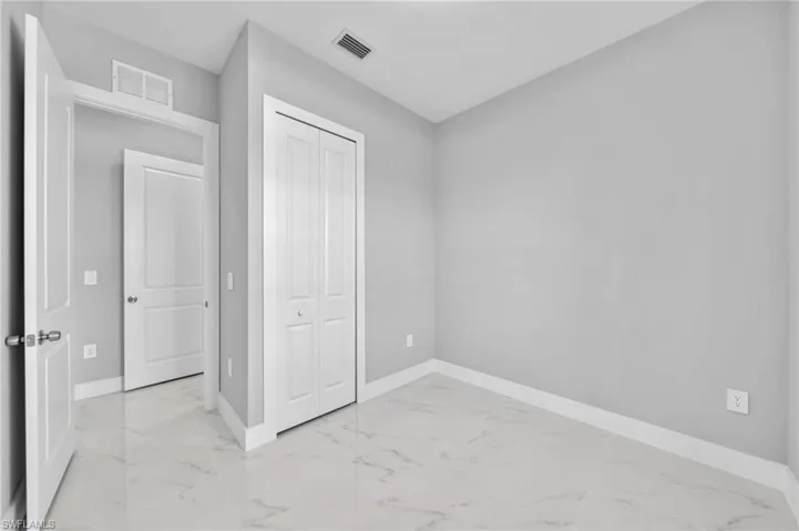 Unfurnished bedroom with light marble finish flooring and a closet