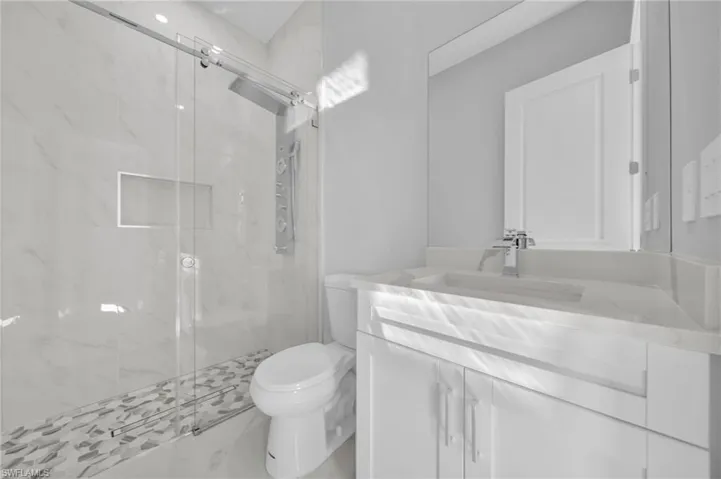 Bathroom featuring vanity, a marble finish shower, and marble look tiles